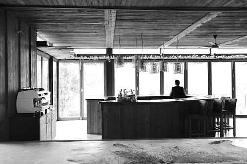 man standing inside bar counter in grayscale photo